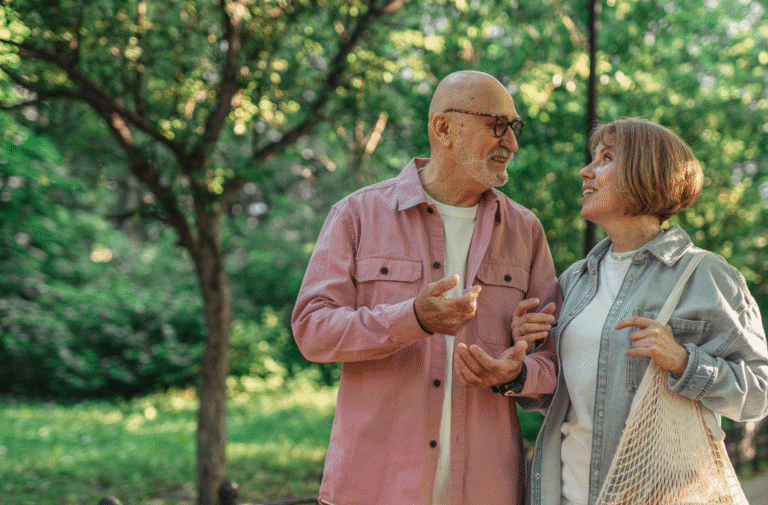 Smiling senior couple walking together in a park, enjoying a relaxed conversation about their future and retirement plans.