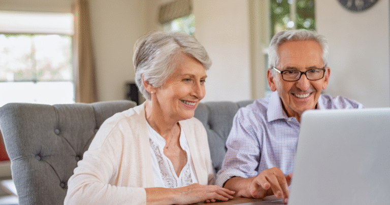 Smiling senior couple reviewing their retirement plan and minimum distribution requirements on a laptop at home.